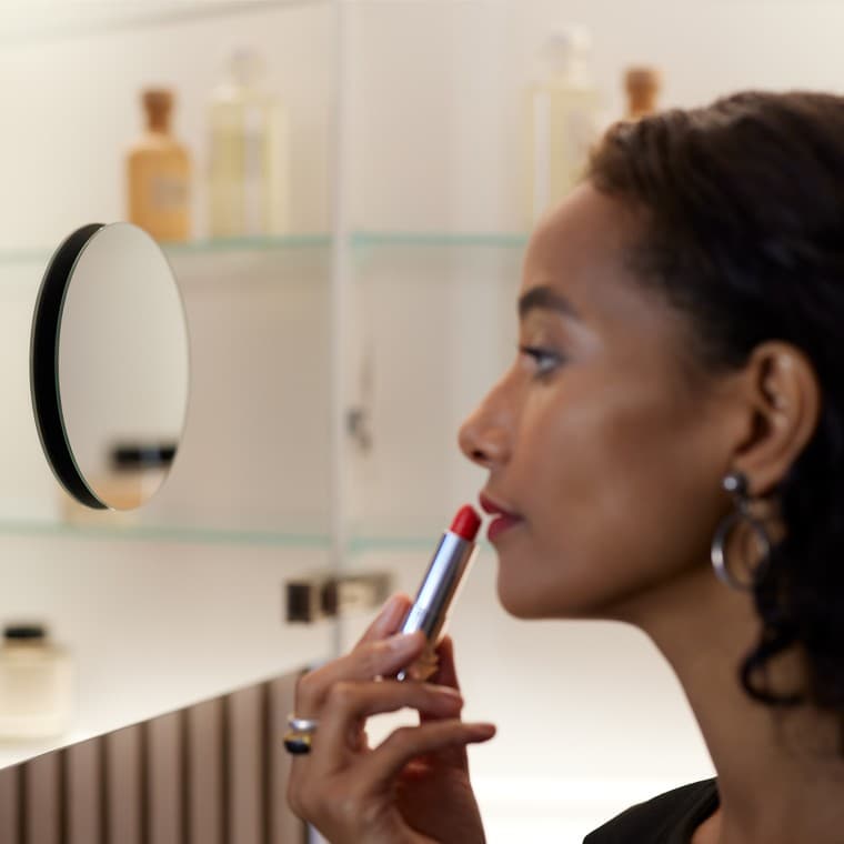 Prikaz žene koja upotrebljava ogledalo za šminkanje Prikaz žene koja upotrebljava ogledalo za šminkanje